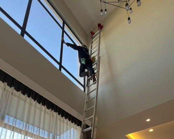 A tall ladder set against a double-height glazed wall