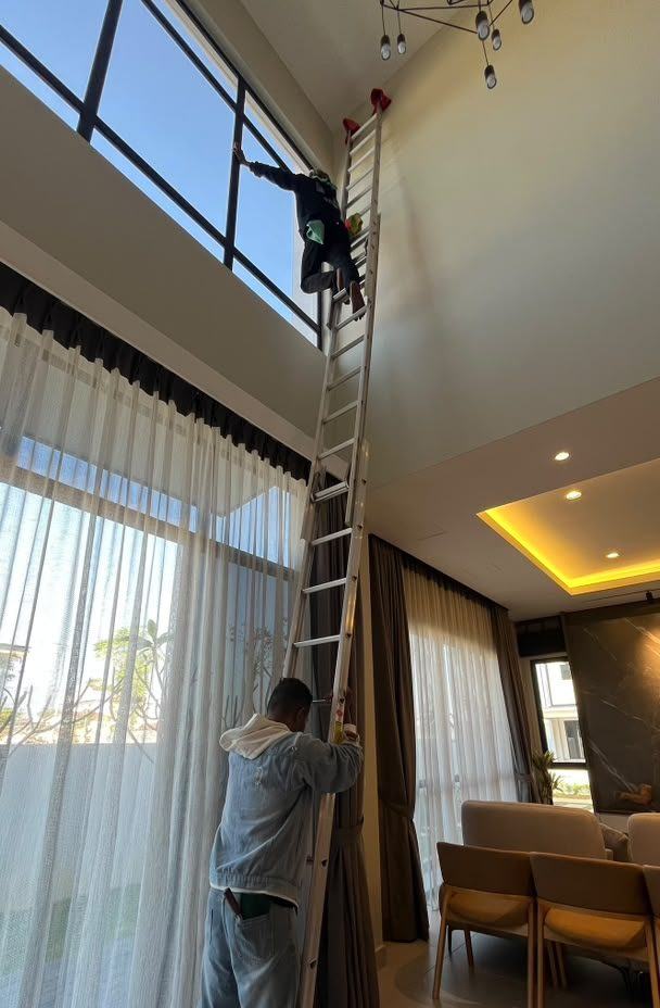 Two cleaners on ladders working along a glazed wall